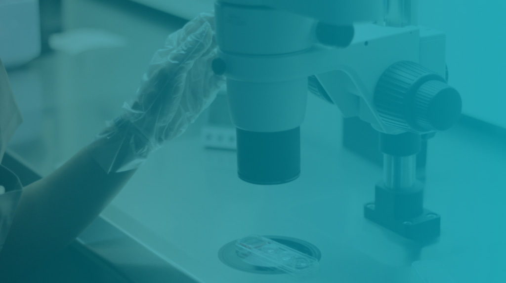 Close-up of a gloved hand adjusting a laboratory microscope beside a petri dish, teal-tinted, clinical and calm mood